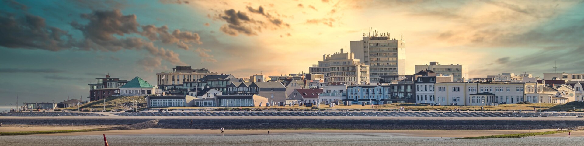 A coastal cityscape with a prominent tower and a beach in the foreground.