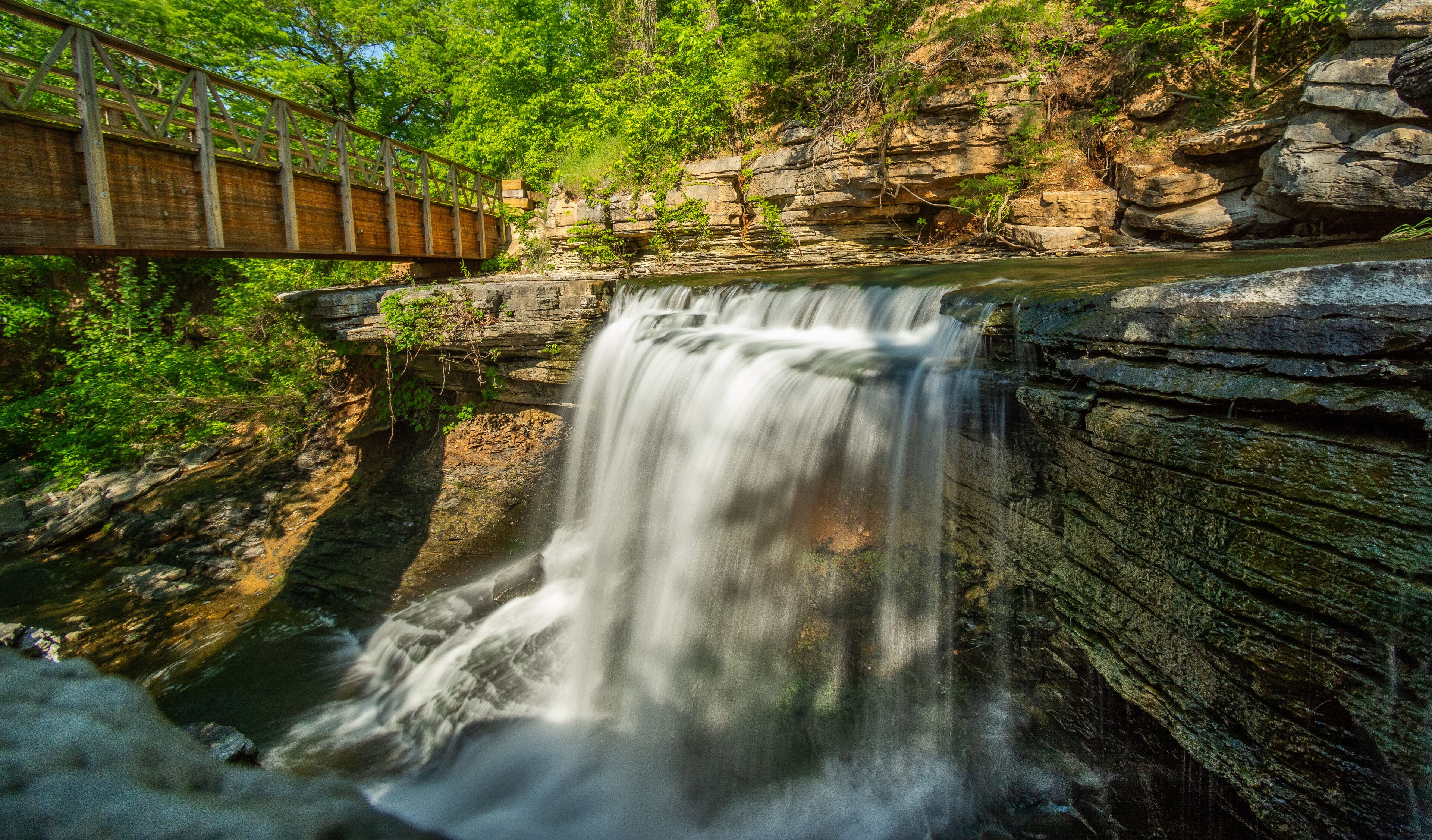 Waterfall Cascading Under Rustic Wooden Bridge in the Ozarks.