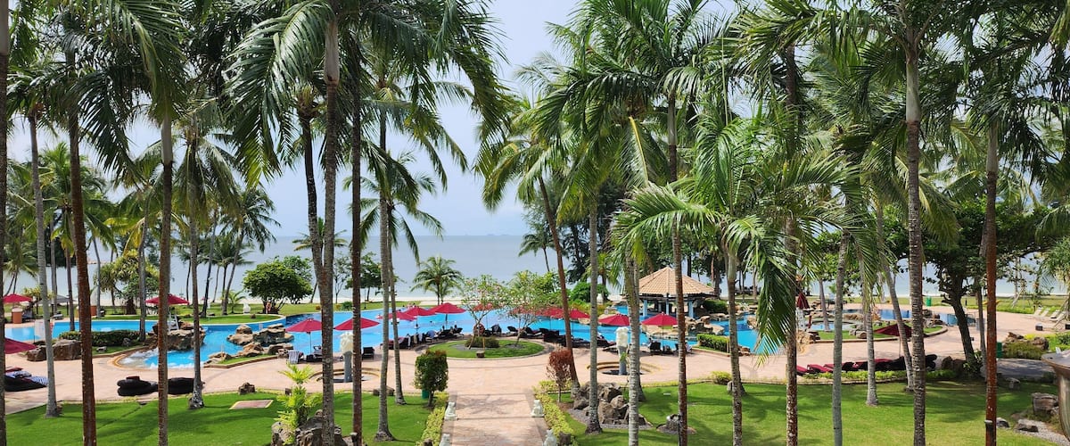 A resort with multiple swimming pools, palm trees, and a view of the ocean.