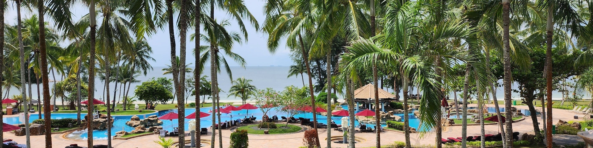 A resort with multiple swimming pools, palm trees, and a view of the ocean.