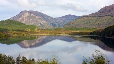 A calm lake surrounded by mountains with autumn foliage.