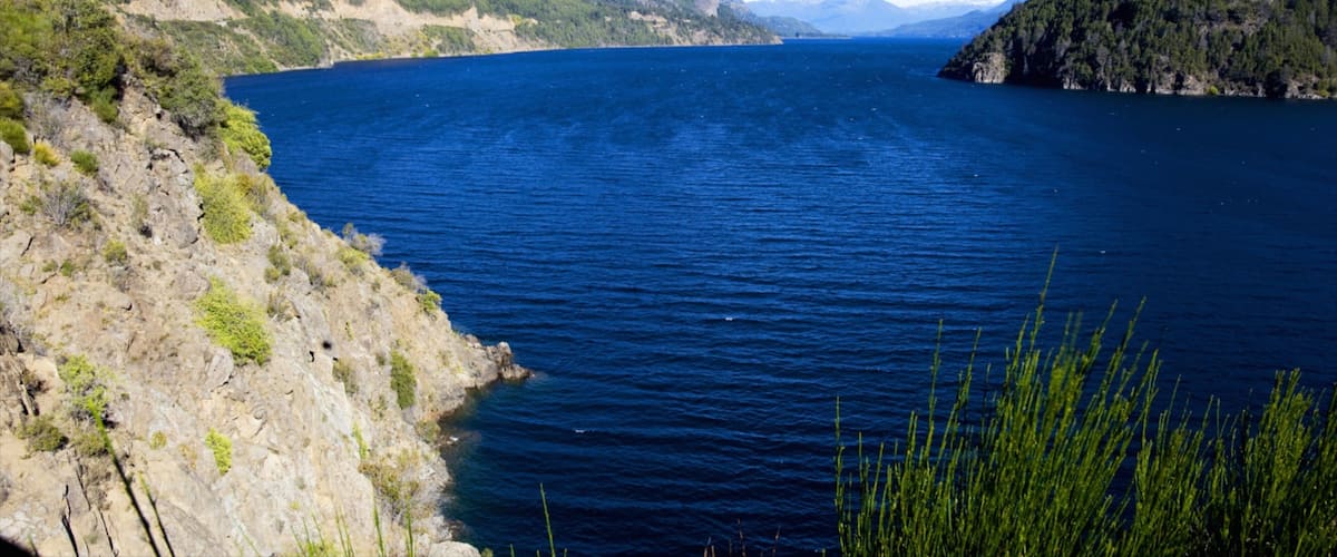A large body of water surrounded by green hills and mountains.