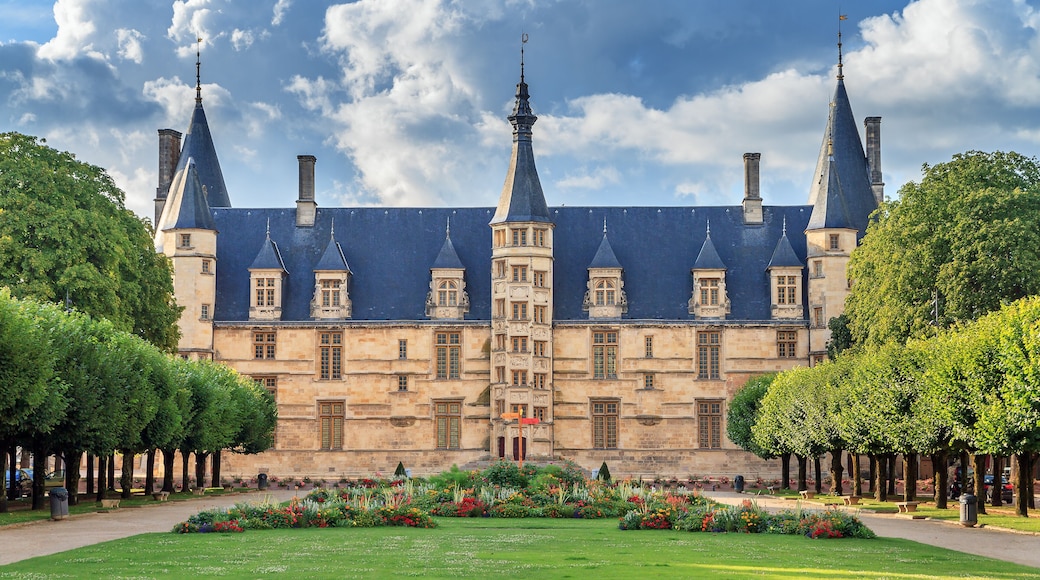 Un bùtiment historique doté de nombreuses flÚches, un jardin bien entretenu et un ciel dégagé.