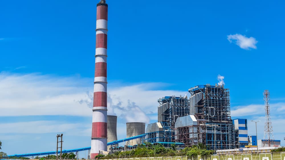 Une centrale électrique dotée d’une haute cheminée, de tours de refroidissement et de bâtiments industriels.