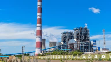 Une centrale électrique dotée d’une haute cheminée, de tours de refroidissement et de bâtiments industriels.