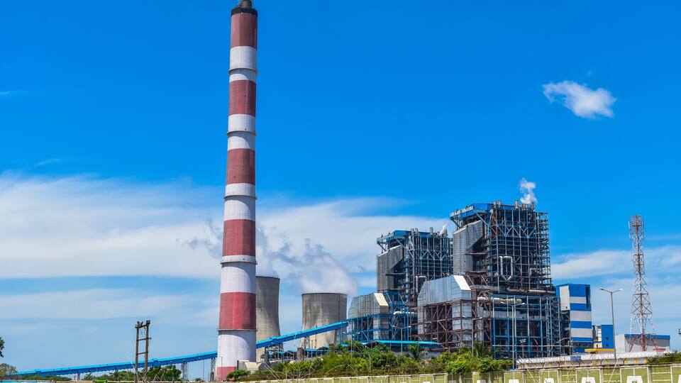 A power plant with a tall chimney, cooling towers, and industrial buildings.
