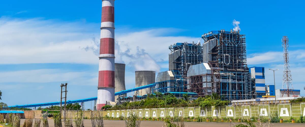 A power plant with a tall chimney, cooling towers, and industrial buildings.