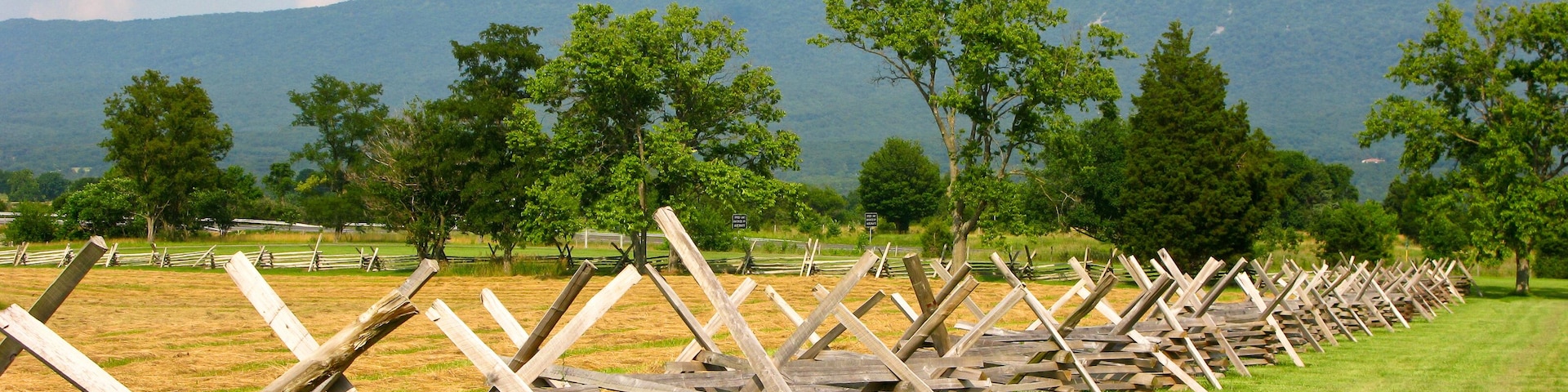 Un campo con vallas de madera y árboles al fondo.