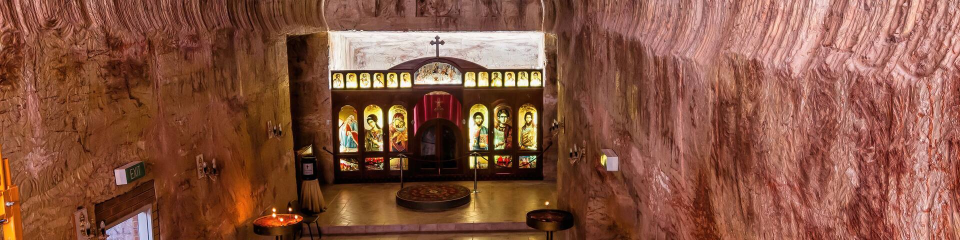 A church interior with a vaulted ceiling, stained glass windows, and a central altar.