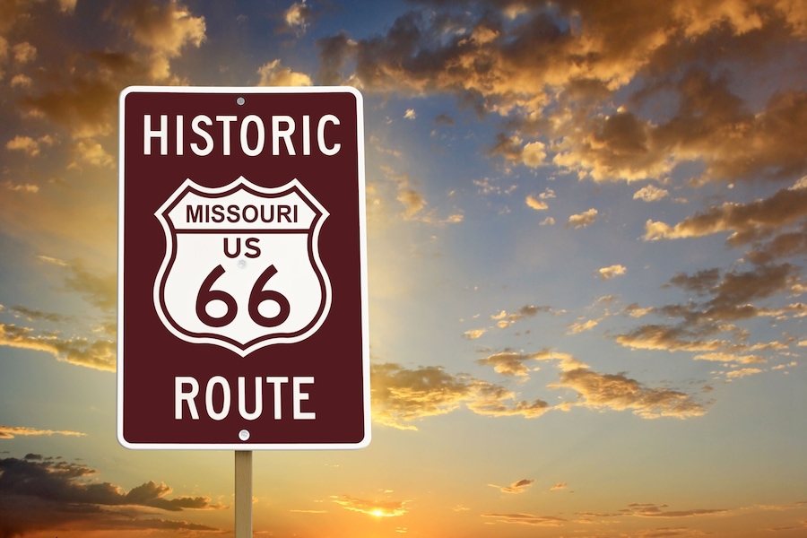 Un panneau historique indiquant le tracé de la route 66 aux États-Unis, dans le Missouri, sur fond de ciel au coucher du soleil.