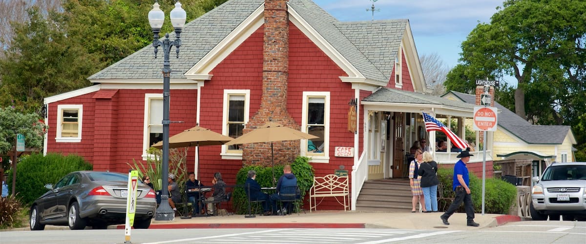 A red brick building with a white porch, a brick chimney, and an American flag.