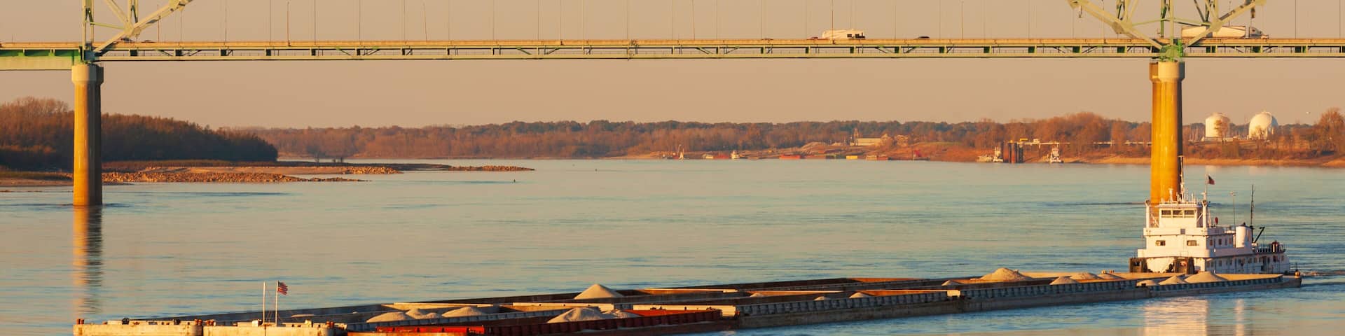 Freight barge carrying cargo on Mississippi river, and Hernando deSoto bridge in Memphis, TN, USA