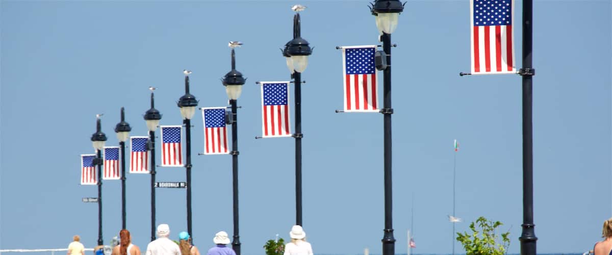 A boardwalk with American flags and street lamps.