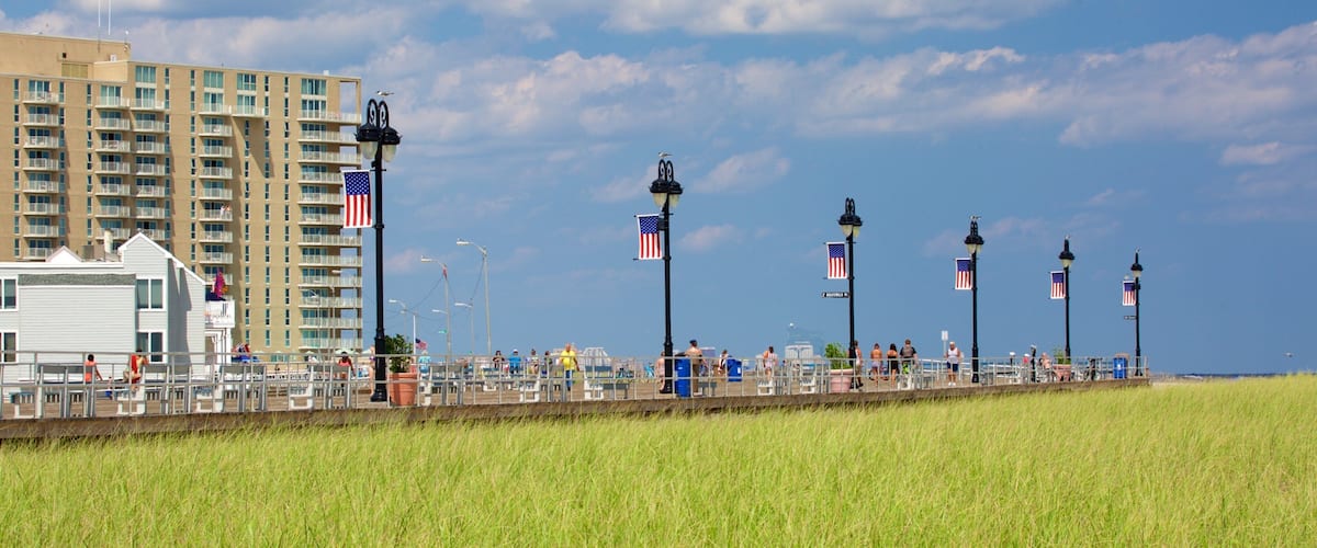 Une promenade en bord de mer, ornée de drapeaux américains, avec une jetée et un immeuble de grande hauteur.