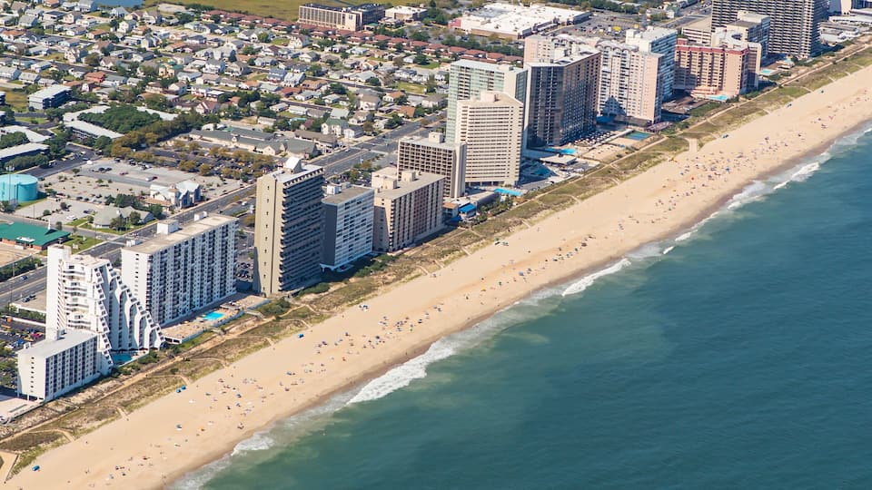 An aerial view of a coastal city with a long sandy beach, high-rise buildings, and a marina.