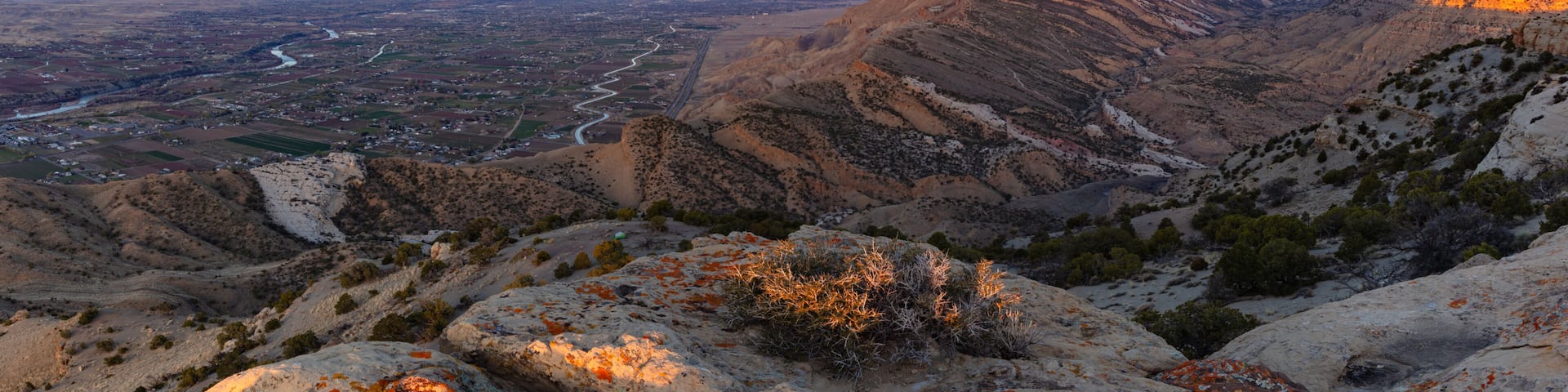 A mountainous landscape with a river valley and a sunset.