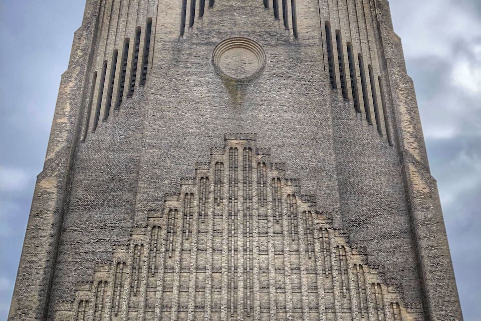 Un edificio alto de ladrillo con techo puntiagudo y ventanas arqueadas.