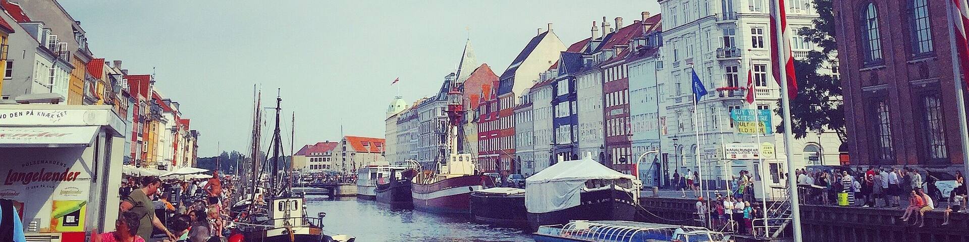 A crowded boat tour along a canal with historic buildings on both sides.