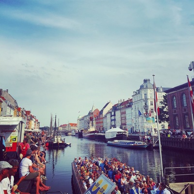A crowded boat tour along a canal with historic buildings on both sides.