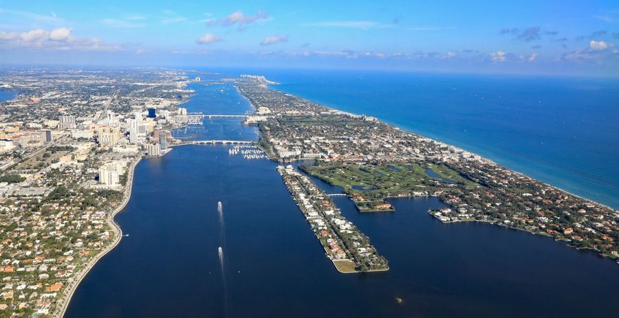 Vista aérea de una ciudad costera con una gran bahía, un puente y un puerto deportivo.
