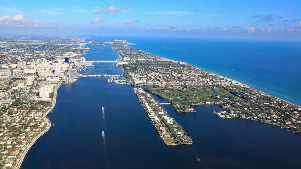 An aerial view of a coastal city with a large bay, a bridge, and a marina.
