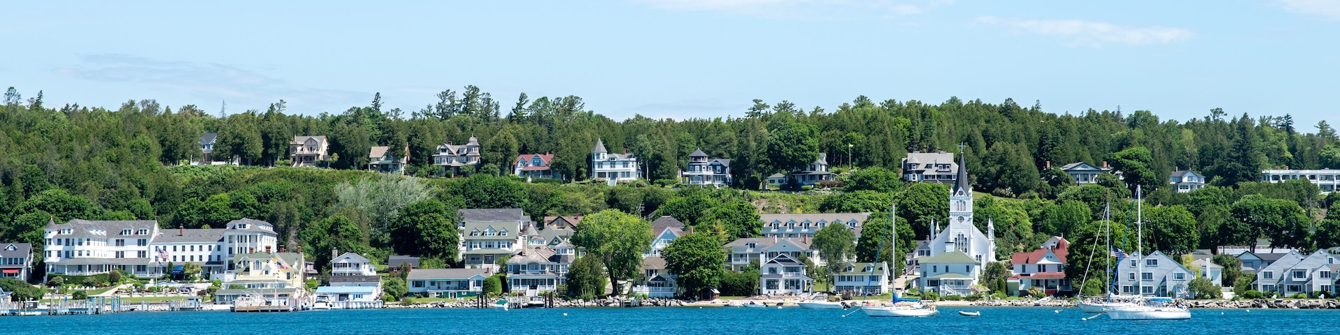 Une ville côtière avec des maisons, une église et des bateaux sur l’eau.