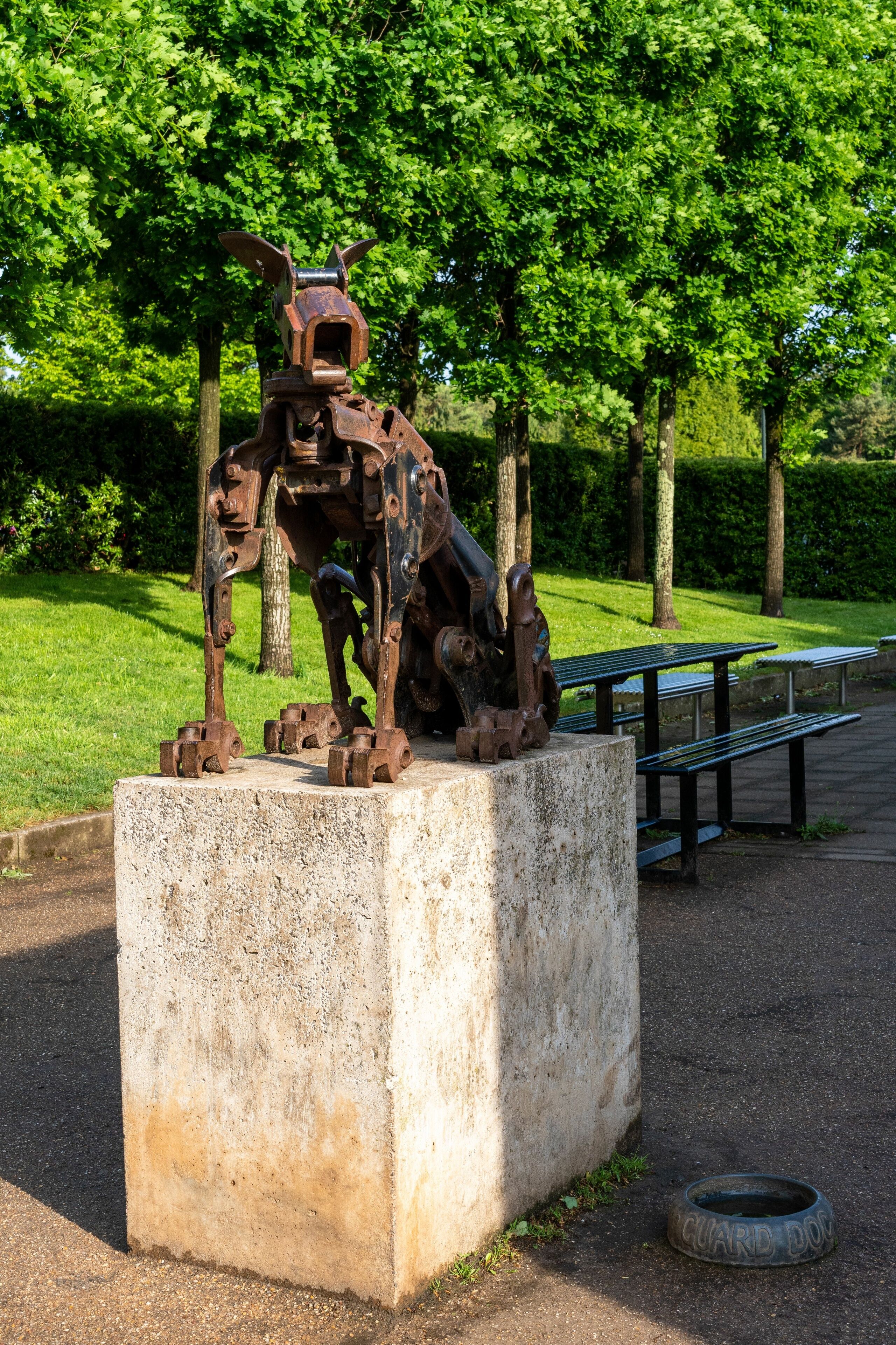 Vertical shot of a metal statue of a dog on a stone plinth in Blaise Castle Estate, Bristol