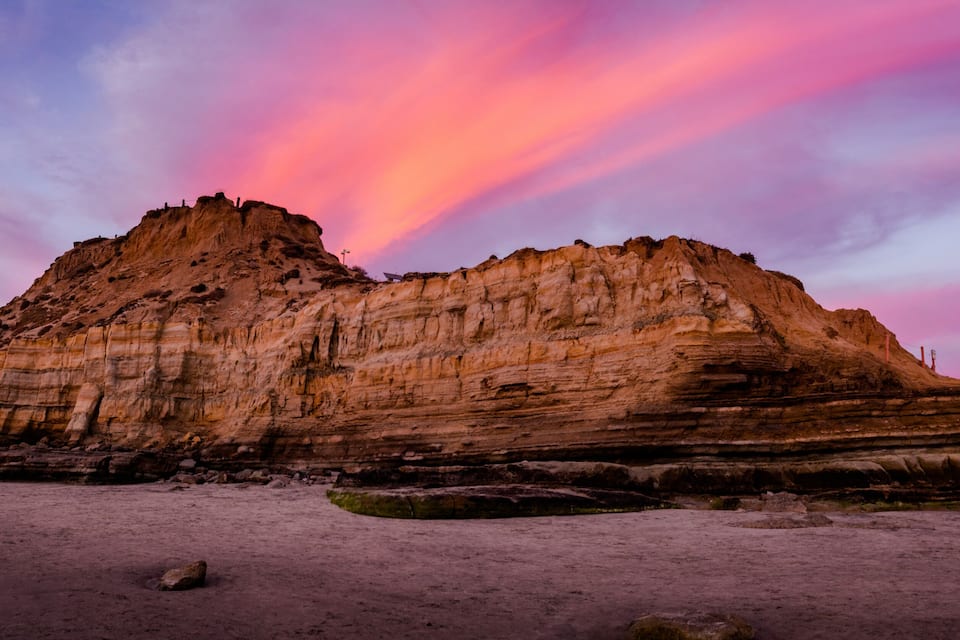 Eine große Felsformation mit schichtartigem Sedimentgestein bei Sonnenuntergang.