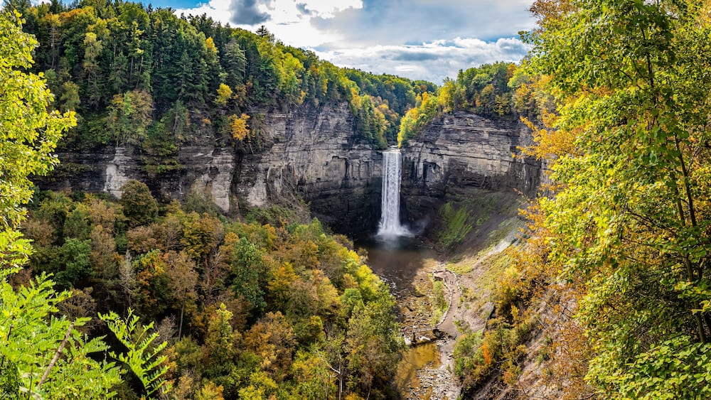 A waterfall surrounded by autumn foliage in a forested gorge.