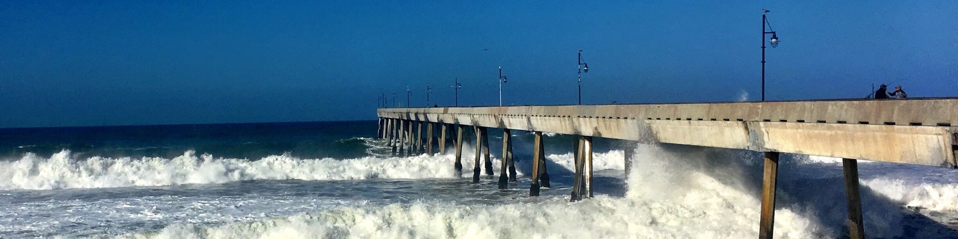 Un muelle se adentra en el océano, con olas rompiendo contra él.