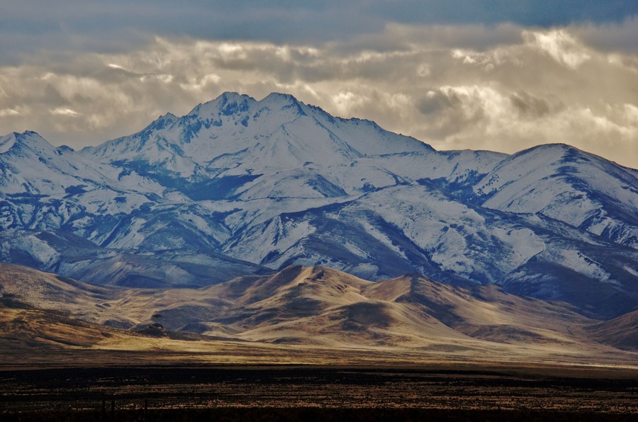 Unusual lighting showcase Snow capped McConnell Peak in shadow with sunlit foothills, Santa Rosa Mountains, Fort McDermitt area, Nevada