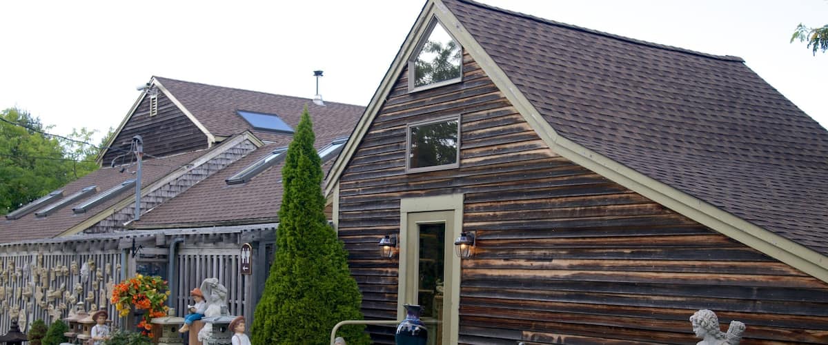A wooden building with a sloped roof, stone benches, and statues.
