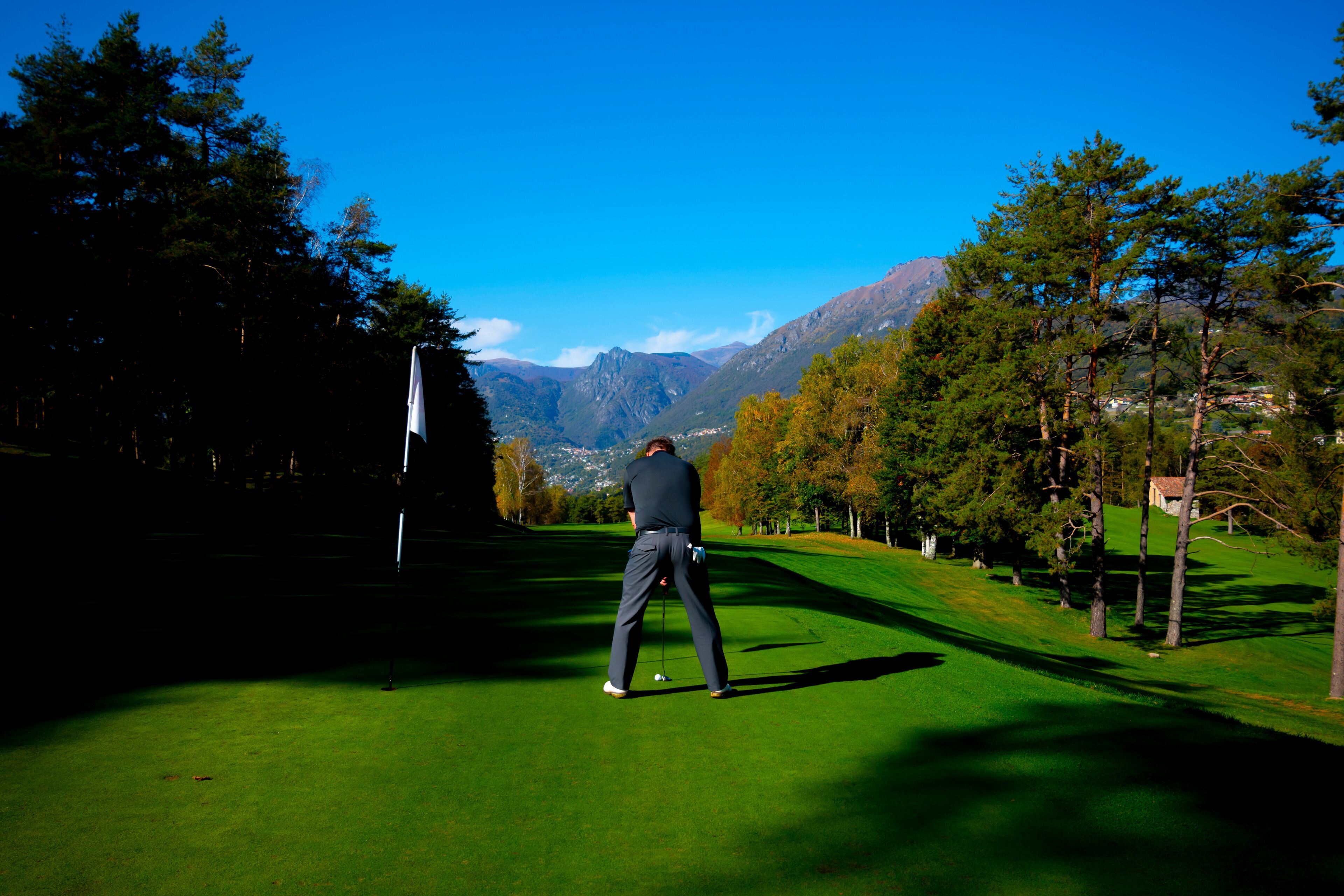 Golfer on Putting Green on Golf Course Menaggio with Mountain View in Autumn in Lombardy, Italy.