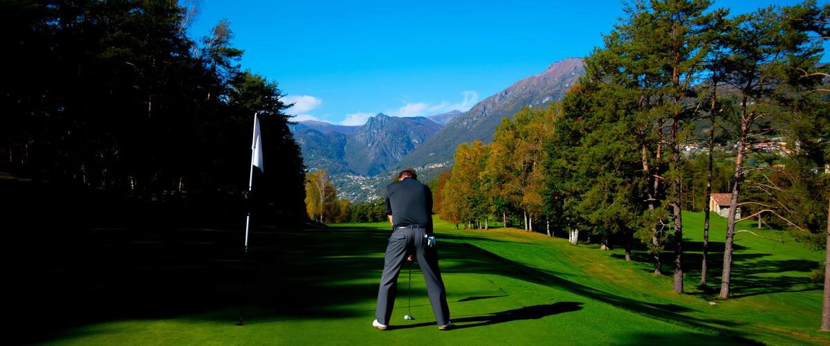 Golfer on Putting Green on Golf Course Menaggio with Mountain View in Autumn in Lombardy, Italy.