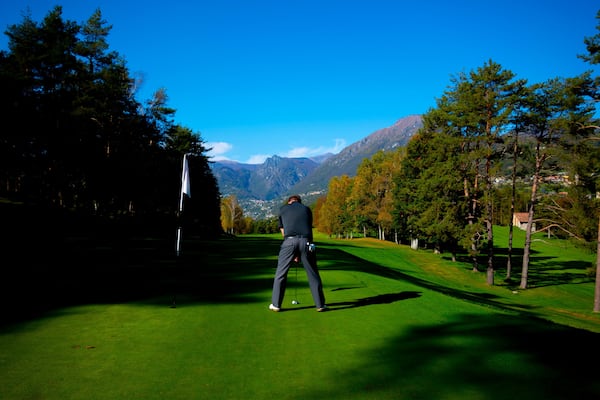 Golfer on Putting Green on Golf Course Menaggio with Mountain View in Autumn in Lombardy, Italy.