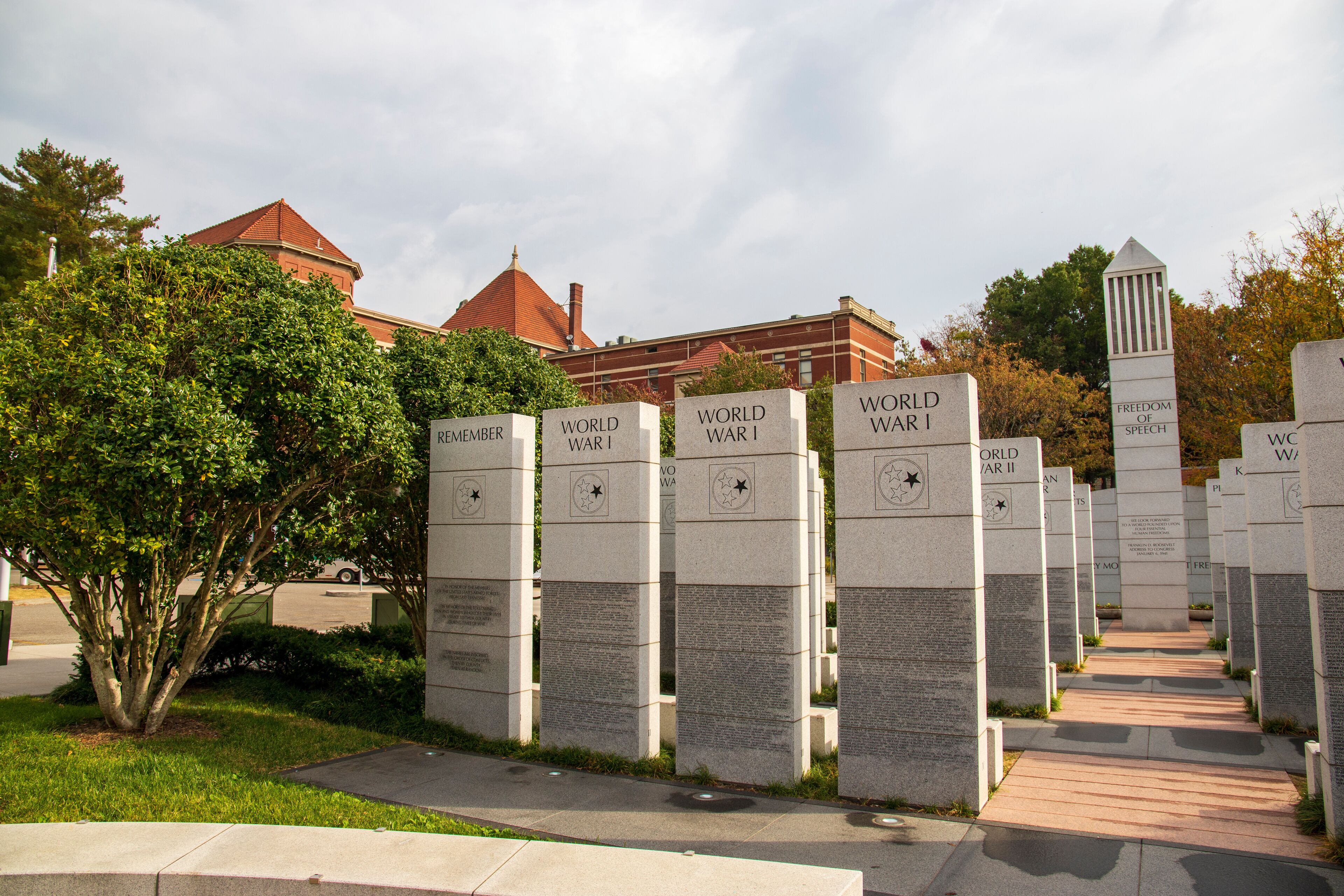 a gorgeous autumn landscape at East Tennessee Veterans Memorial in World's Fair Park with stone slabs surrounded by autumn colored trees and lush green trees and cloudy sky in Knoxville Tennessee USA