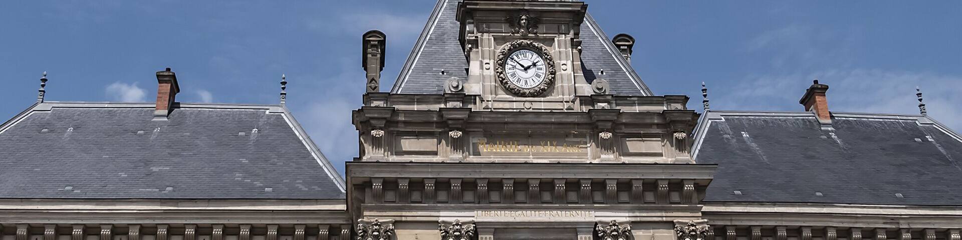 A historic building with a clock tower, flags, and classical architecture.