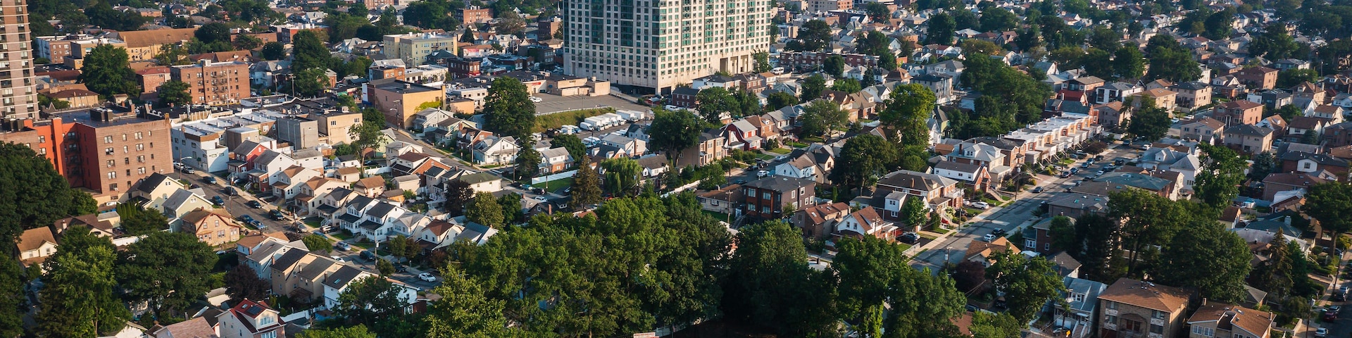 Zona urbana densamente poblada con una mezcla de edificios residenciales y comerciales, un gran edificio central y un horizonte lejano.