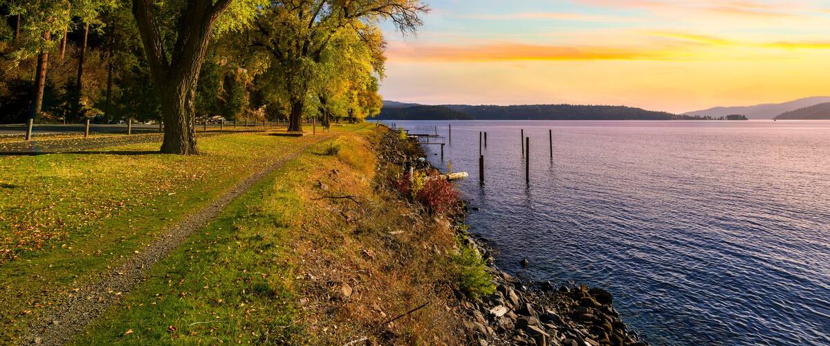 Autumn sunset view with fall colors on the leaves along the tree lined Centennial Trail path as it makes it's way along the lake near Silver Beach in Coeur d'Alene, Idaho USA.