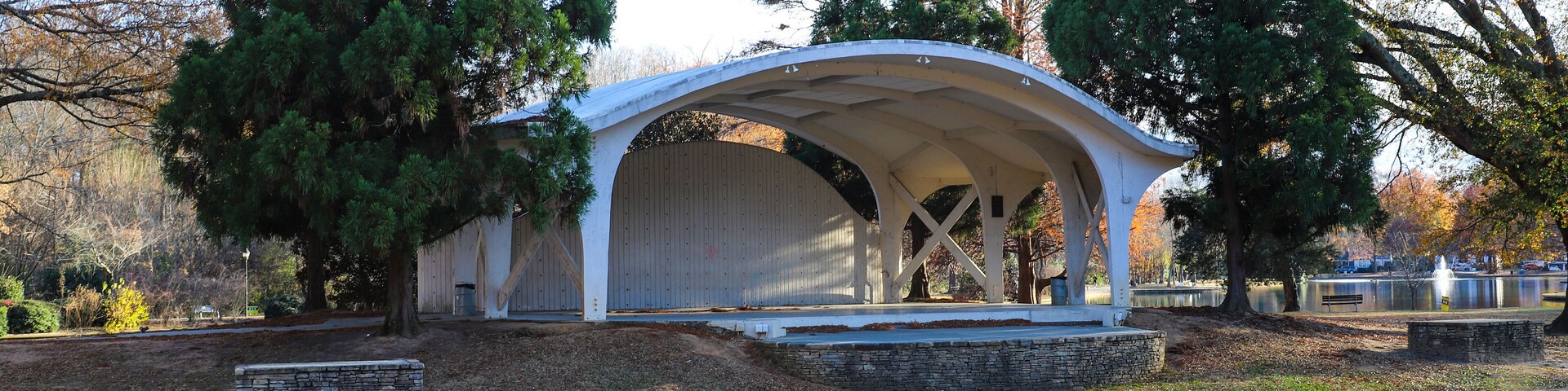 a shot of a curvy white amphitheater in the park surrounded by gorgeous autumn colored trees near a lake with a long smooth winding footpath at Freedom Park in Charlotte North Carolina USA