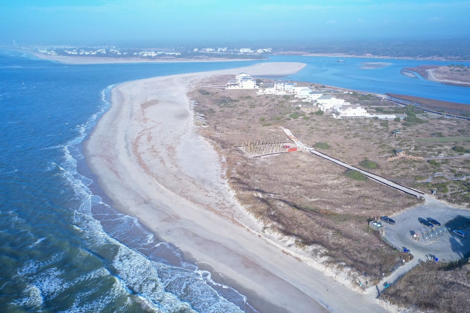 Un paysage côtier avec une plage de sable, une jetée et un espace de stationnement.