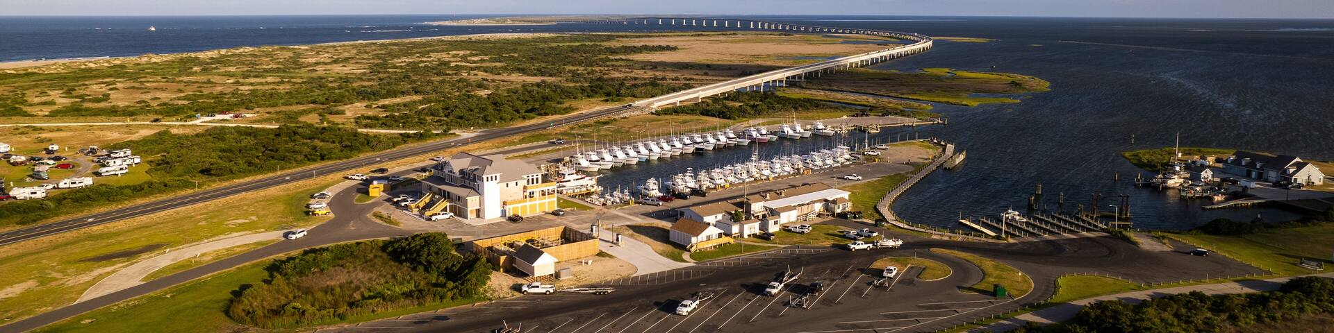 Un port de plaisance situé sur la côte, avec des bateaux, un pont et une autoroute.