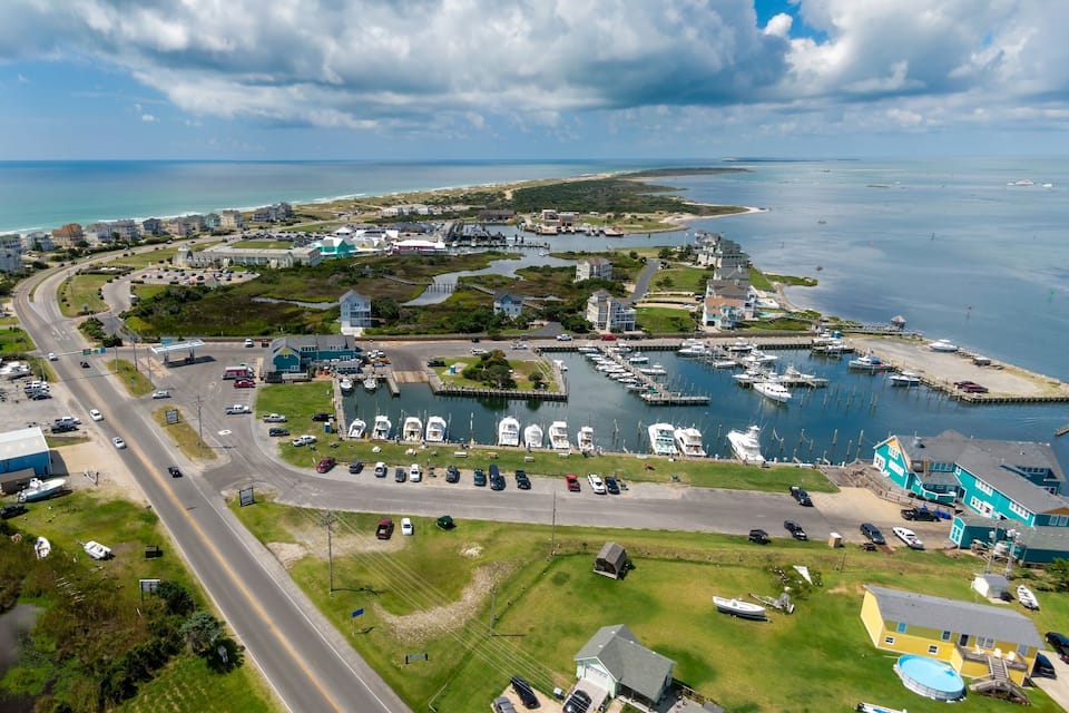 An aerial view of a coastal town with a marina, roads, and residential buildings.