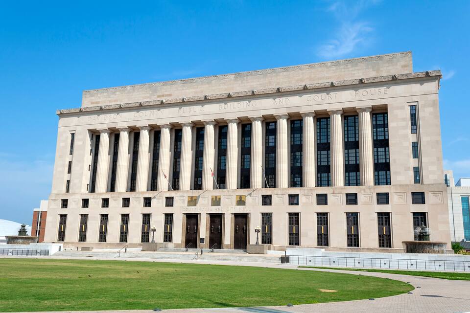 Un grand bâtiment de style néoclassique, doté de colonnes et d’une entrée centrale.
