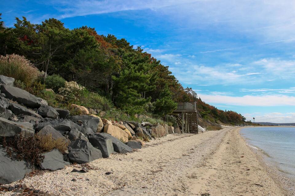 Una playa arenosa con rocas grandes y árboles.
