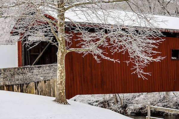 This covered bridge is covered with fresh snow