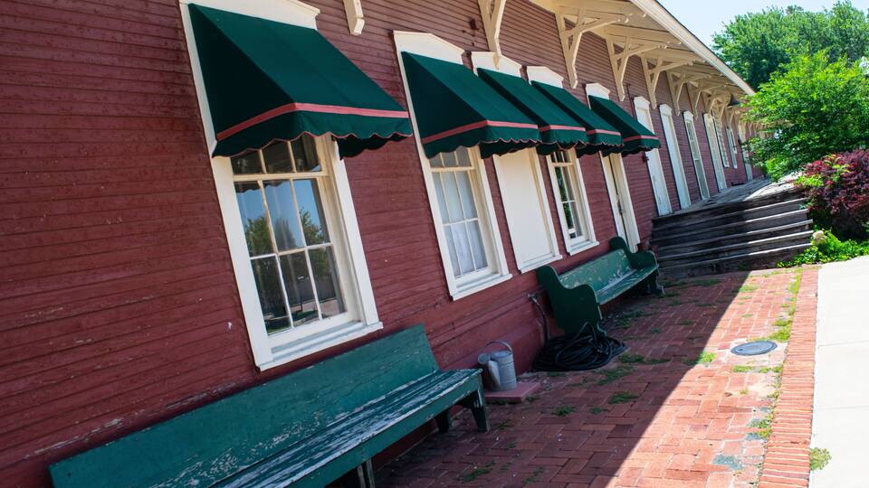 A red building with green awnings and a brick pathway.
