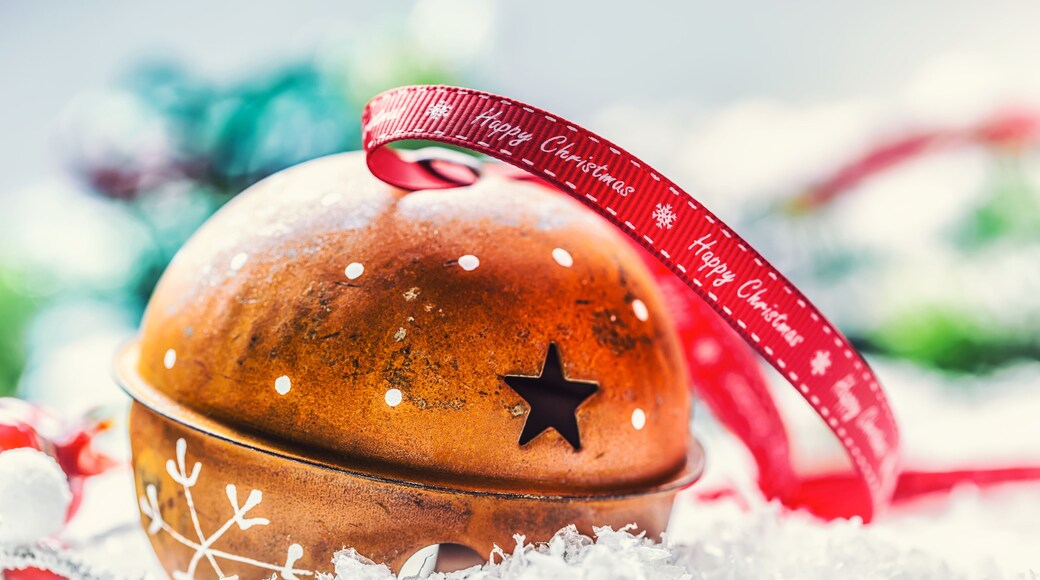 Christmas balls jingle bells. Red ribbon with text Happy Christmas. Snowy abstract background and decoration.