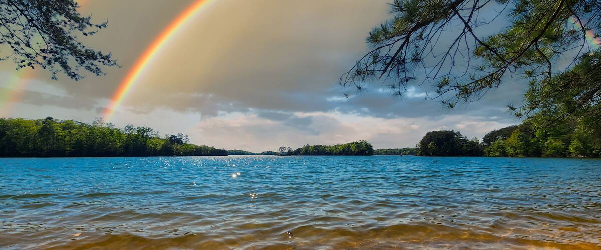 a gorgeous spring landscape at Lanier Point Park with rippling blue water surrounded by lush green trees and plants with blue sky, clouds and a rainbow at Lake Lanier in Gainesville Georgia USA