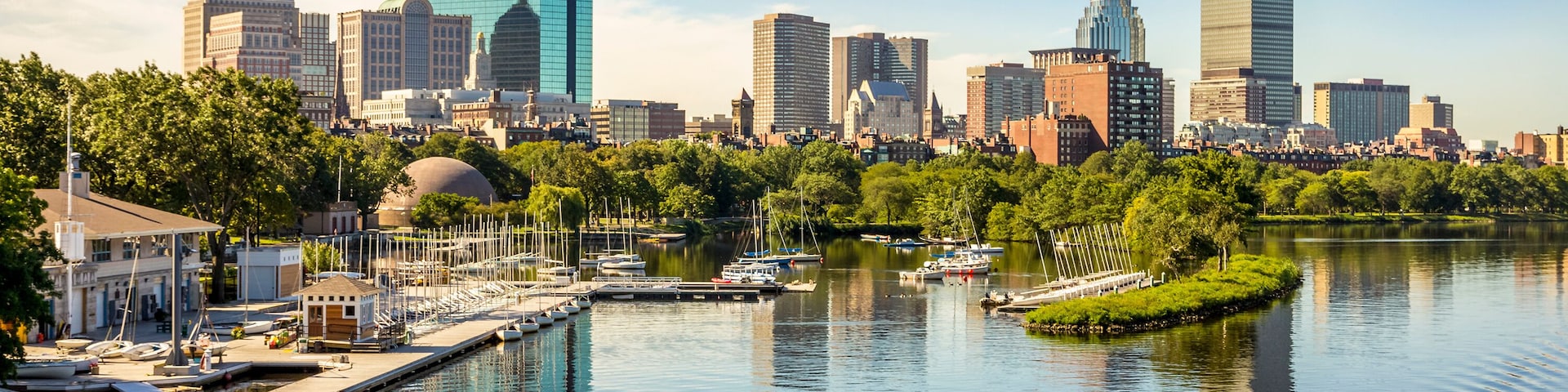 Un horizonte urbano con rascacielos modernos, un río con barcos y un parque con árboles.